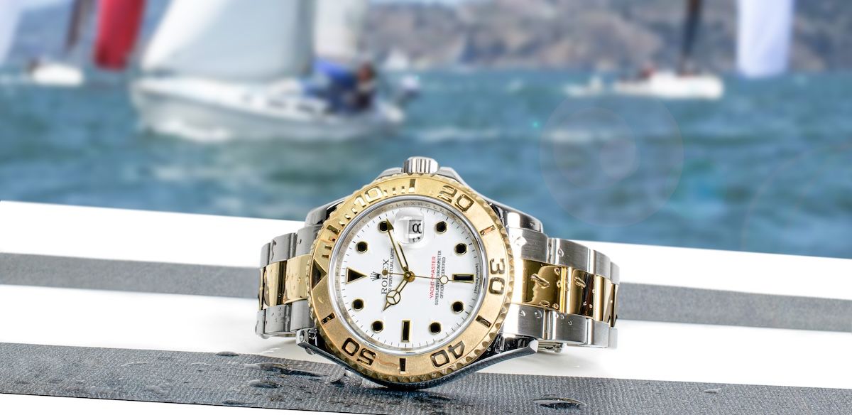 Two-tone Yacht-master laying on its side with sailboats in the background