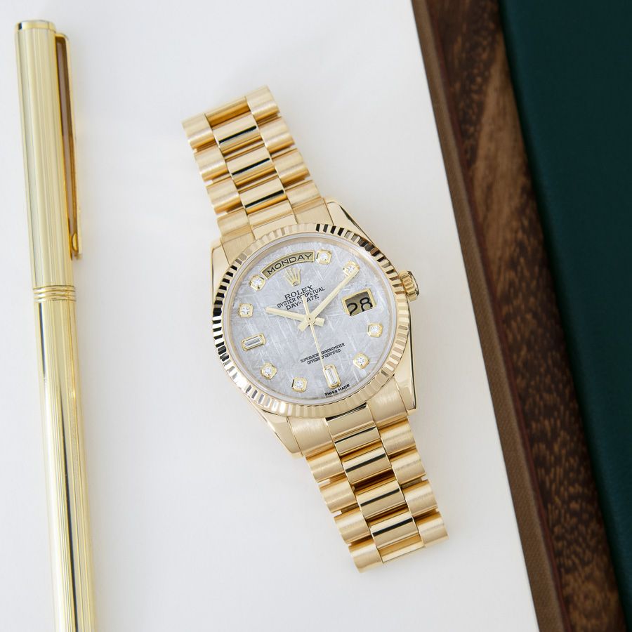 Rolex Day-Date 36 118238 in 18k Yellow Gold with a Meteorite Diamond Dial A top-down photo of the Rolex Day-Date 36 118238 in 18k Yellow Gold with a Meteorite Diamond Dial on a book next to a gold pen