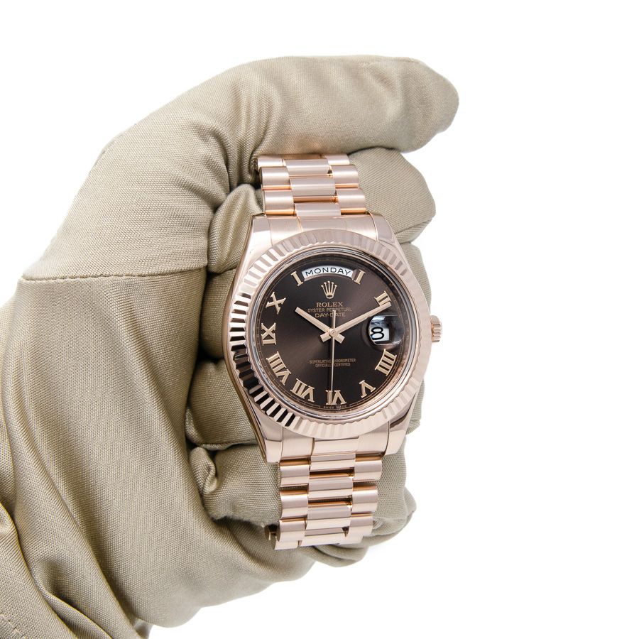 Rolex Day-Date II 218235 in 18k Rose Gold with a Chocolate Roman Dial A gloved hand holding the Rolex Day-Date II 218235 in 18k Rose Gold with a Chocolate Roman Dial