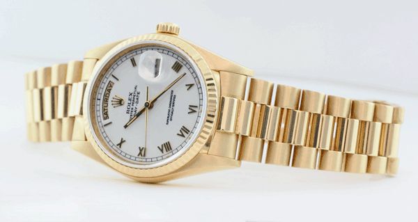 A yellow gold Rolex Day-Date 18038 President White Roman laying down on a white surface